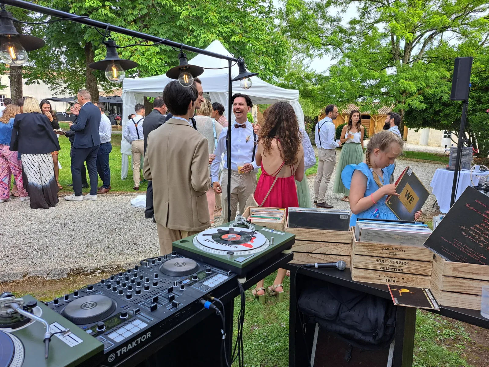 Invités réunis autour des vinyles pendant un cocktail en extérieur