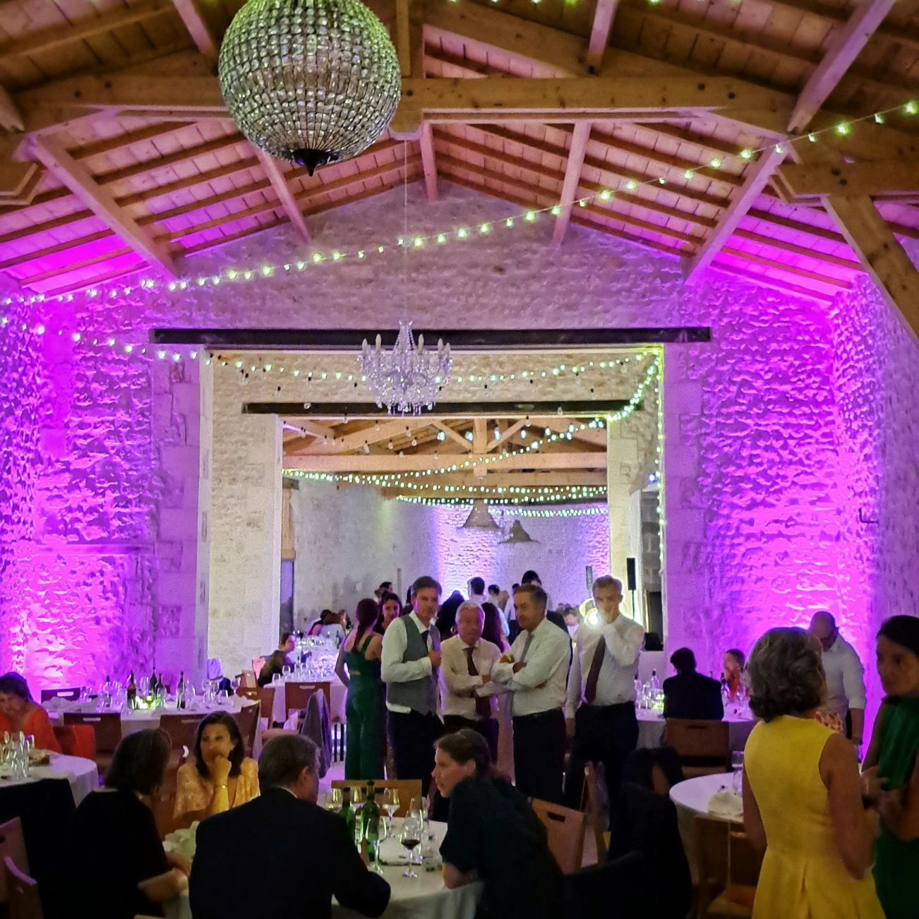 Salle de réception en pierre mise en lumière violette, avec lustres et guirlandes