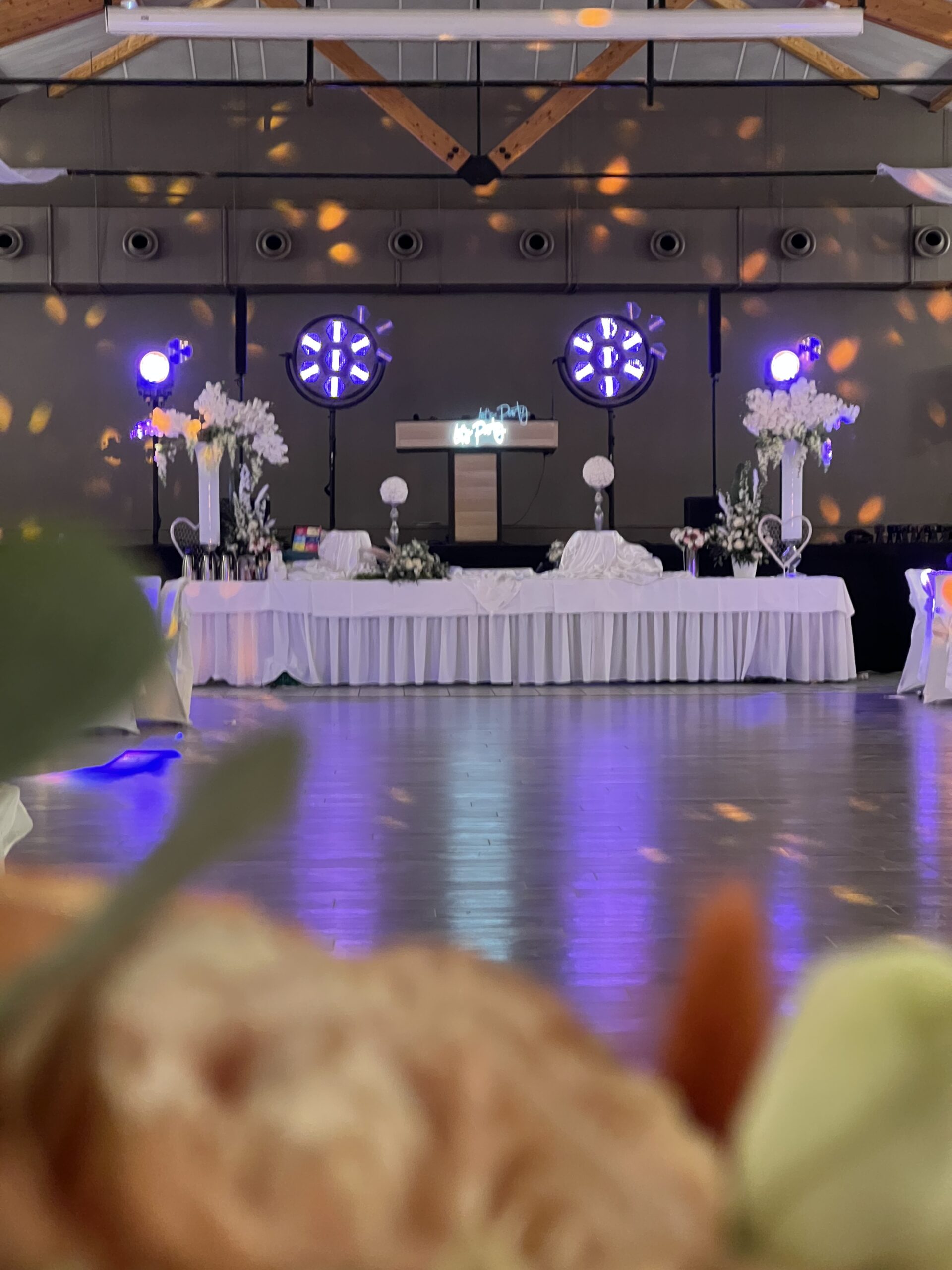 Réception de mariage avec table blanche, compositions florales et éclairages violets